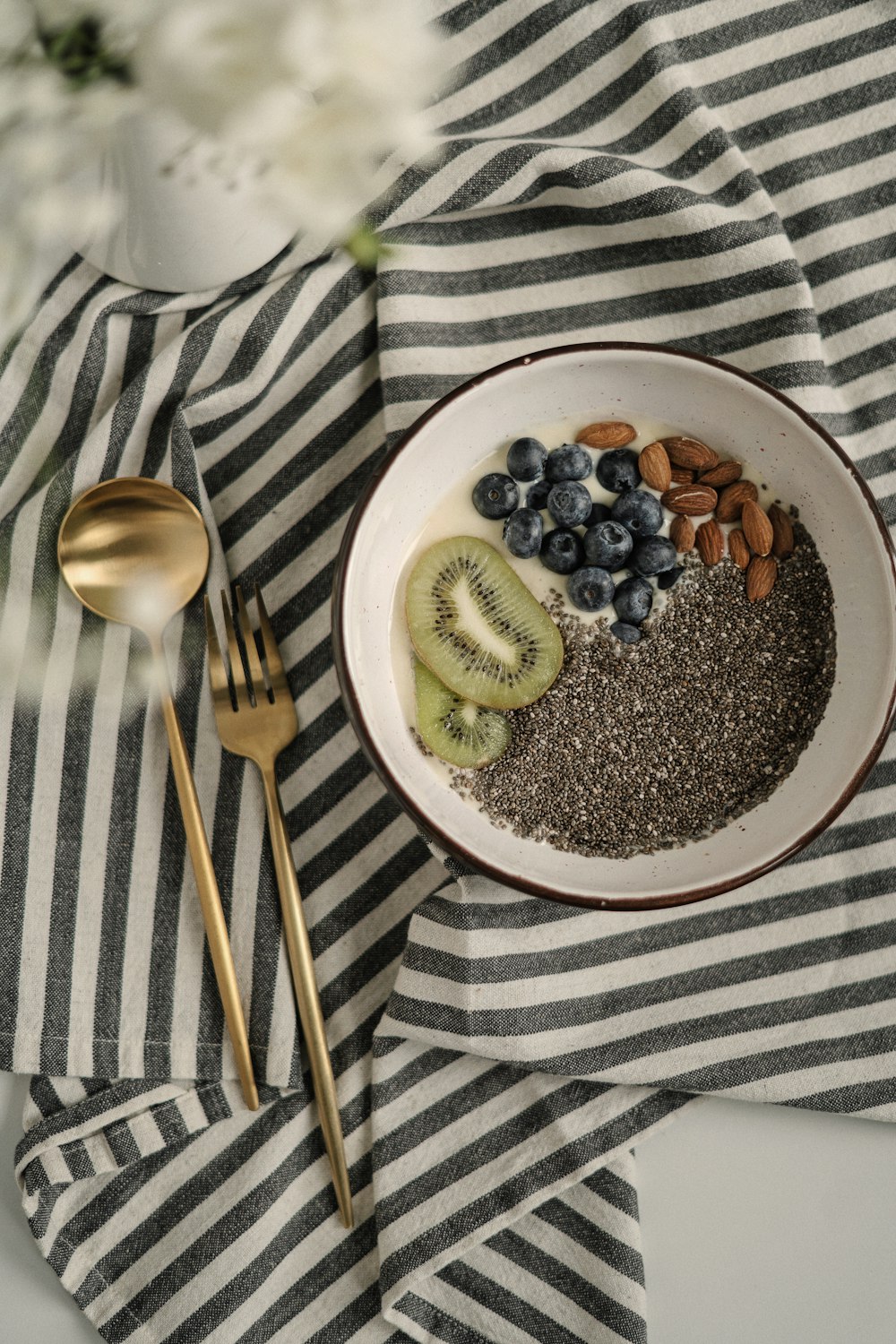 a bowl of cereal with kiwi, blueberries, and bananas