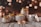 A collection of scented candle jars of various sizes and designs is arranged on a rustic wooden surface. The jars are labeled with the words 'Scented Candle Jar.' The background features a bokeh effect with warm, golden lights, creating a cozy atmosphere.