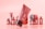 A collection of cosmetic products with a modern packaging design, predominantly in tones of red and pink. The main focus is on a tilted tube with the word 'Mockup' visible, and various other bottles and jars are blurred in the background.
