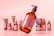 A group of cosmetic containers is displayed against a soft pink background. The central focus is a large amber bottle with a pump, featuring a label with text. Other containers, including tubes and jars, are blurred in the background, creating a sense of depth.