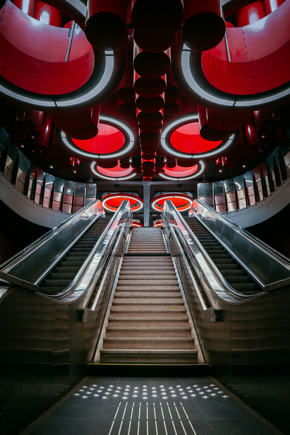 an escalator in a building with red lights