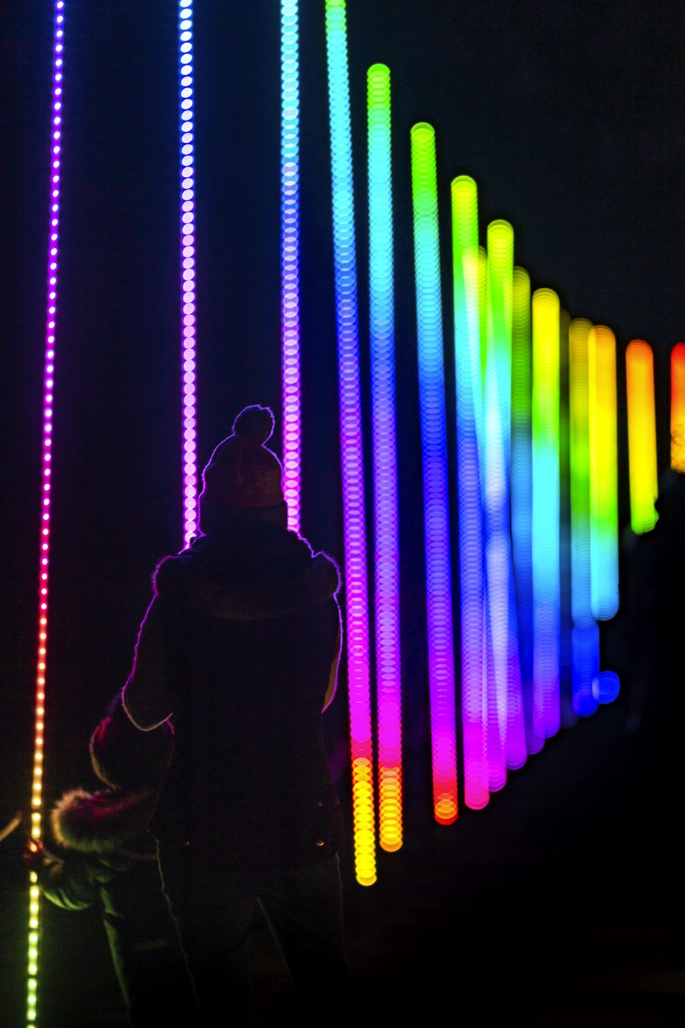 uma pessoa em pé na frente de uma parede colorida do arco-íris
