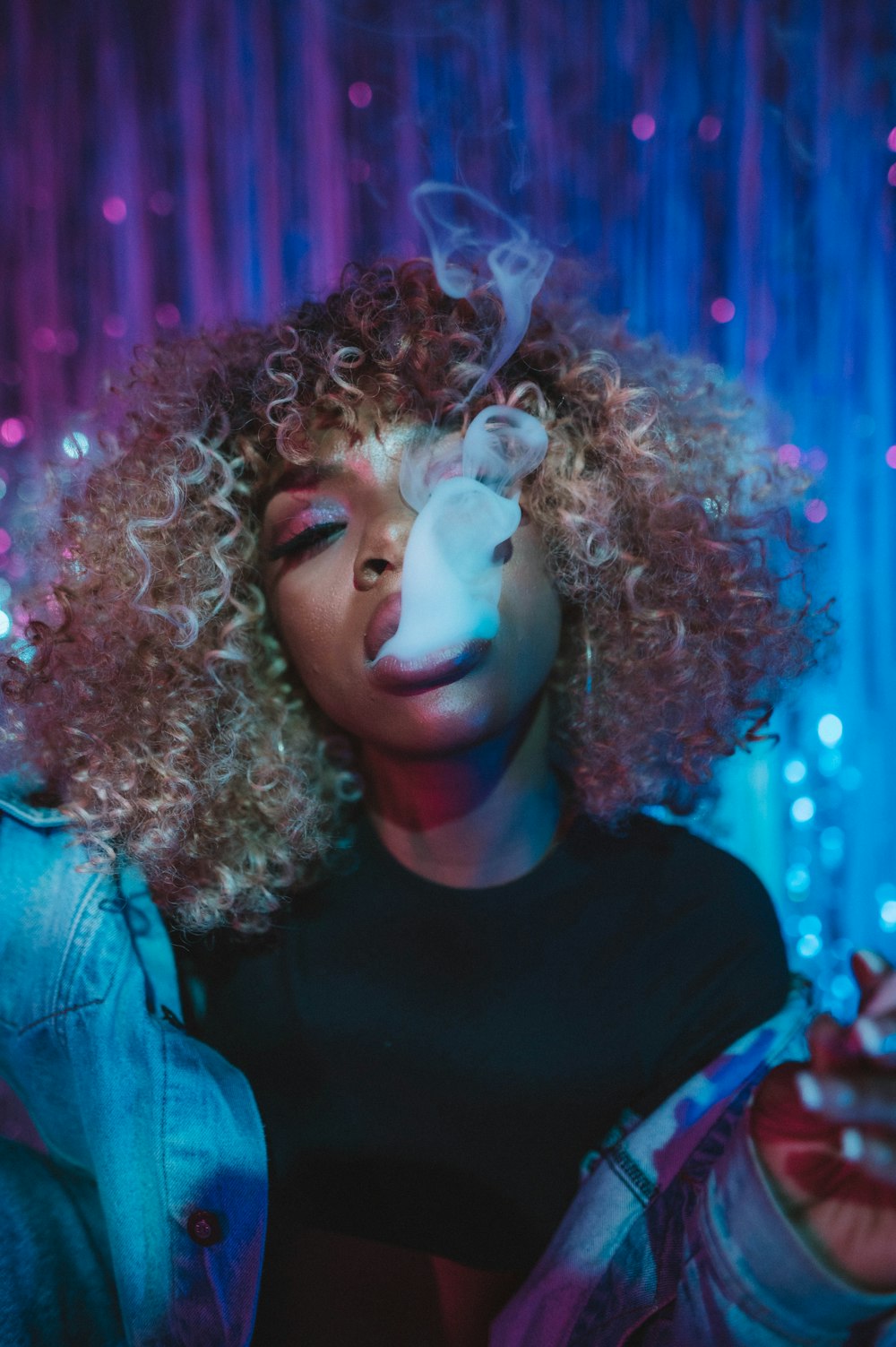 a woman with curly hair smoking a cigarette