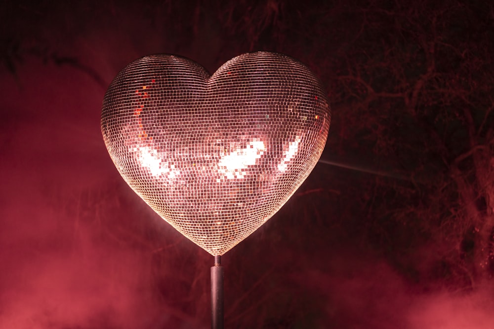 a large heart shaped light up on top of a pole