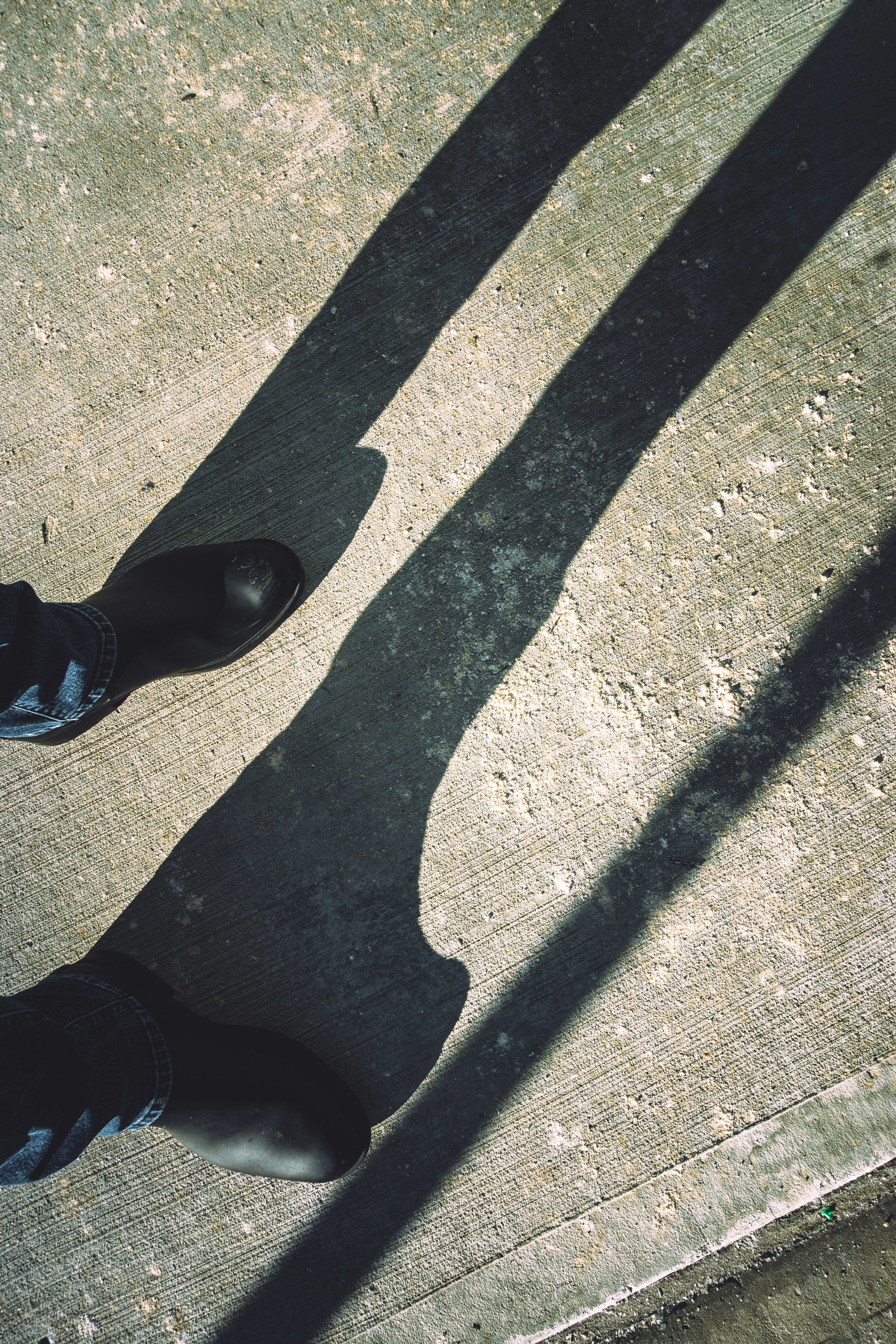 Black shorts on dark concrete surface, stark overhead lighting creating dramatic shadows
