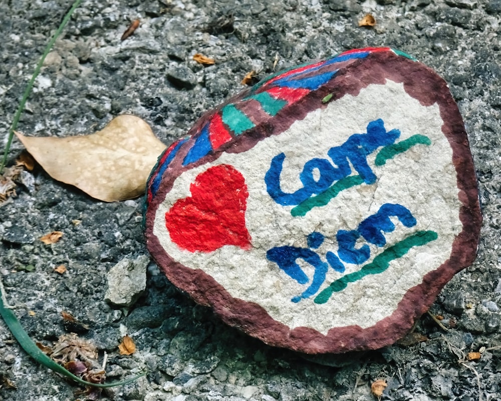 a painted rock with a leaf on the ground