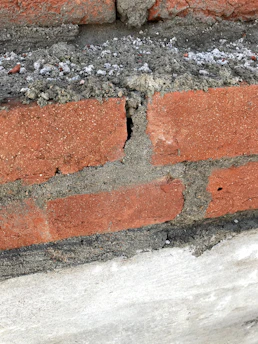 Close-up of hands repairing cracked fireplace bricks with care.