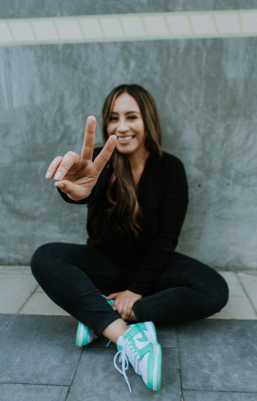 a woman sitting on the ground making a peace sign