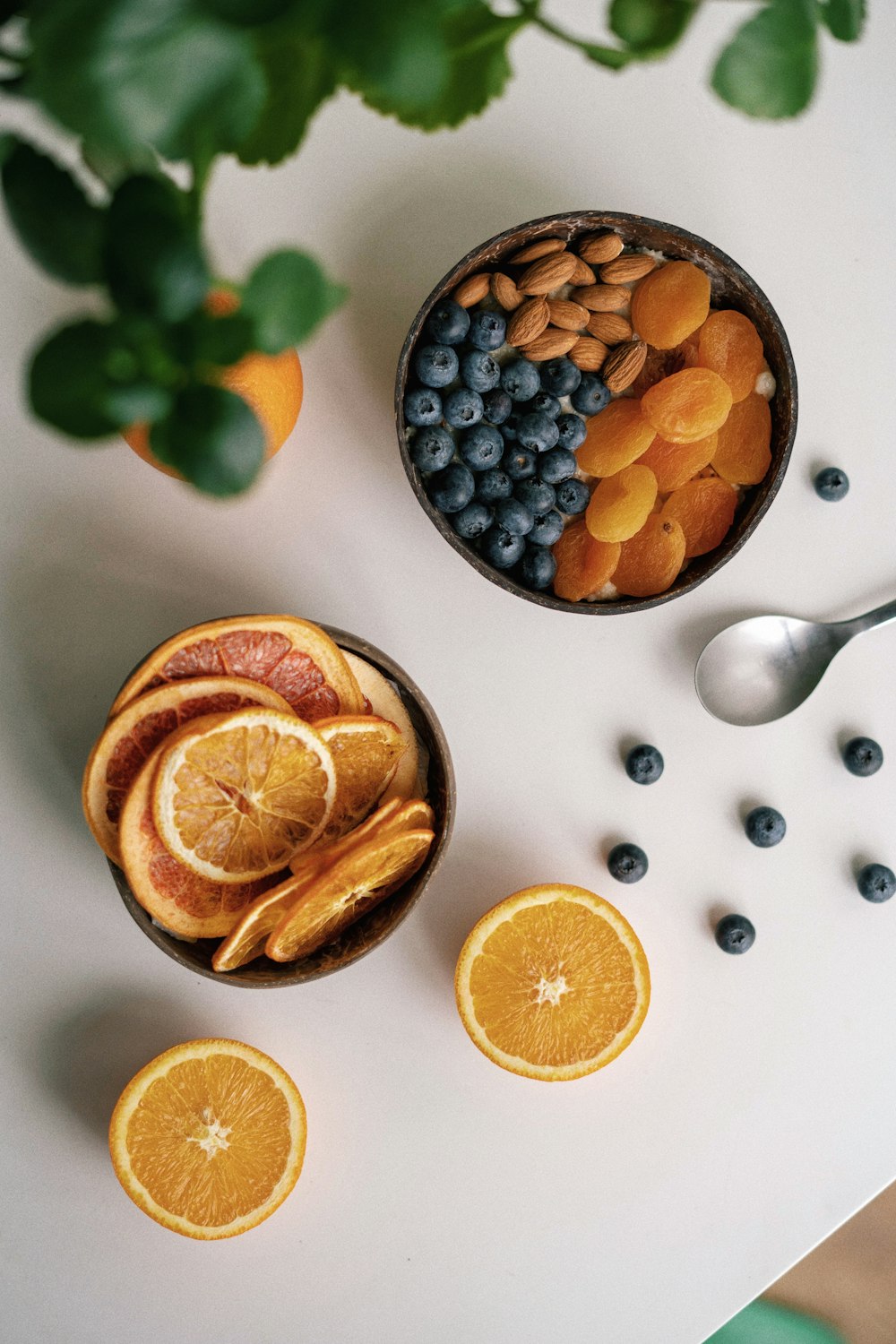 a bowl of oranges, blueberries, and almonds on a table