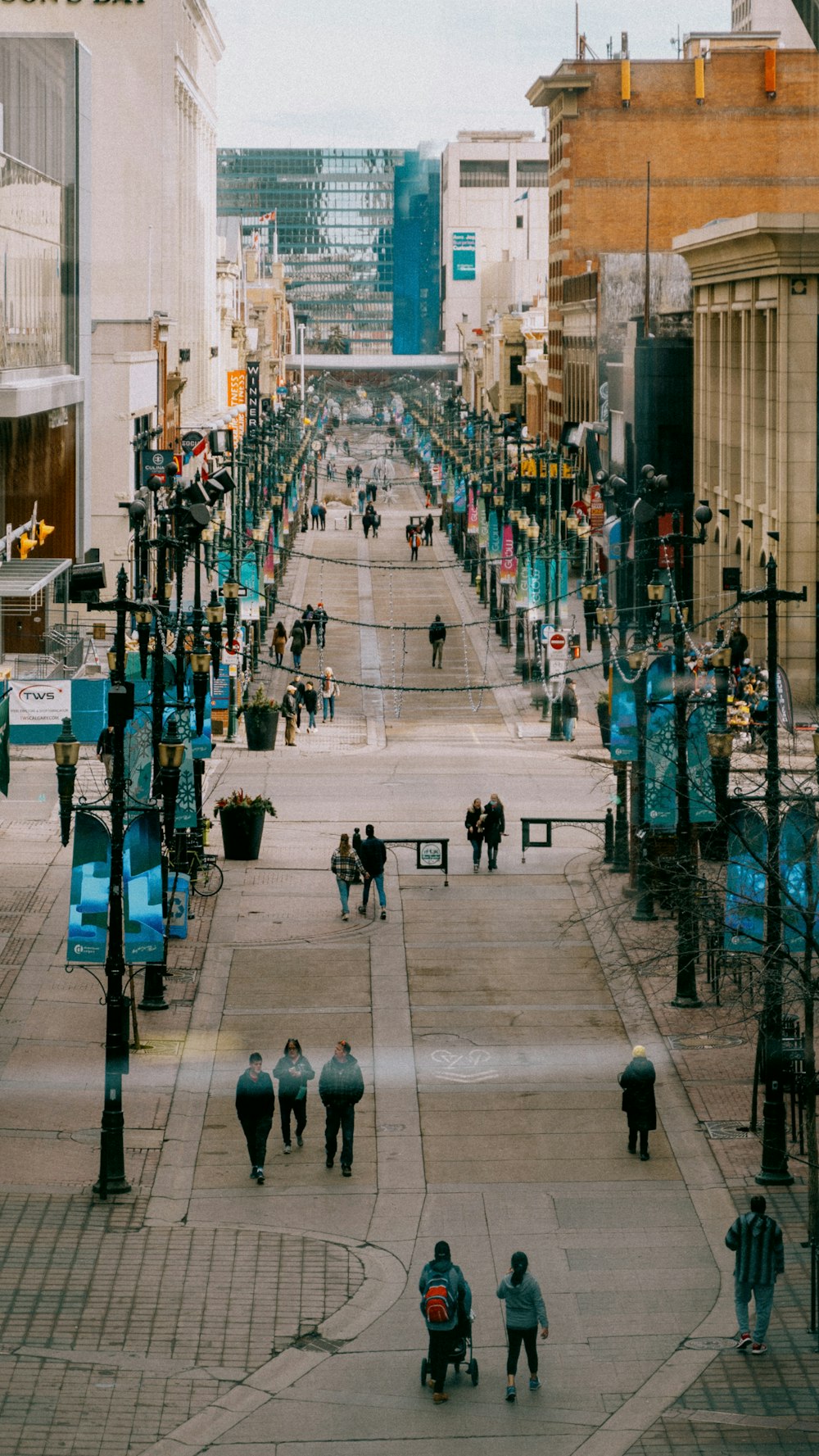 a group of people walking down a street next to tall buildings