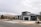 Modern suburban houses with clean lines and a minimalist design are visible. The first house has a multi-car garage and is painted in neutral colors with dark accents. The landscaping includes rocks and drought-resistant plants.