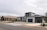Modern suburban houses with clean lines and a minimalist design are visible. The first house has a multi-car garage and is painted in neutral colors with dark accents. The landscaping includes rocks and drought-resistant plants.