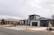 Modern suburban houses with clean lines and a minimalist design are visible. The first house has a multi-car garage and is painted in neutral colors with dark accents. The landscaping includes rocks and drought-resistant plants.