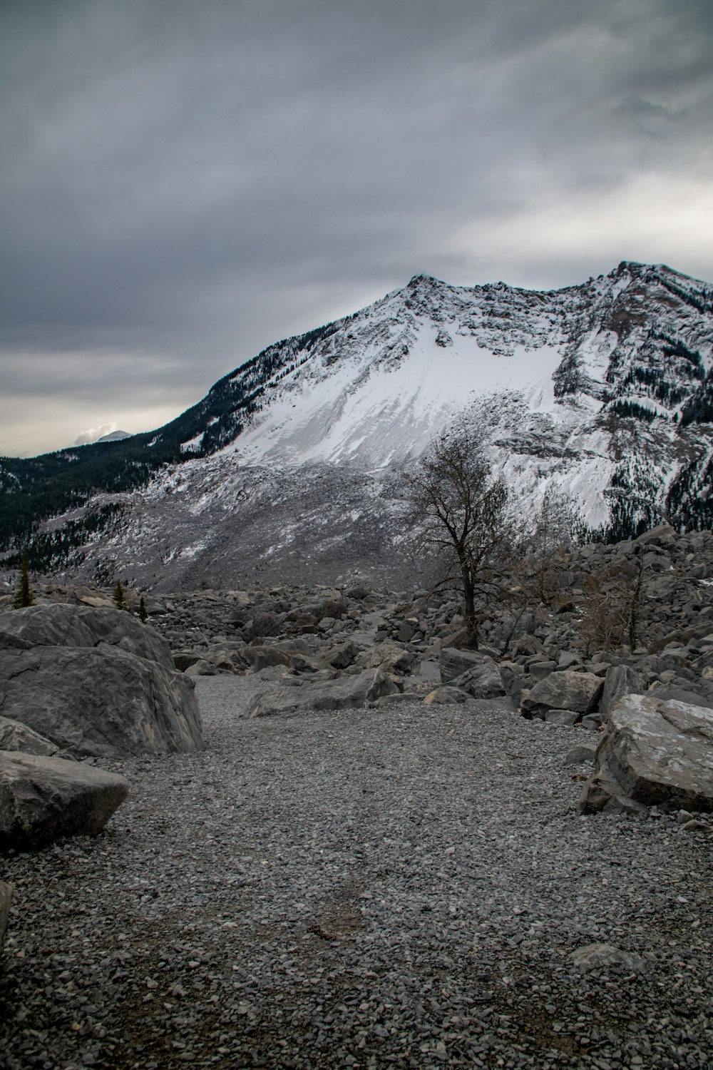 a mountain covered in snow and rocks under a cloudy sky