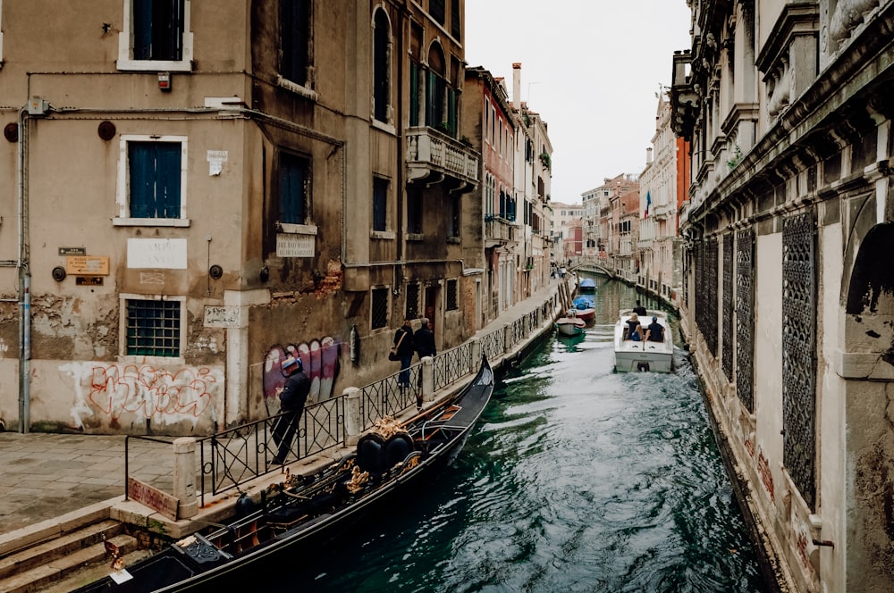 a boat traveling down a canal next to tall buildings