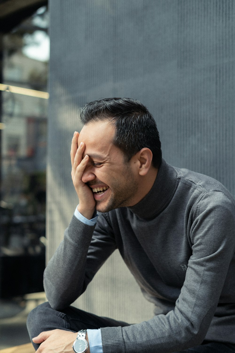 a man sitting on a bench holding his hand to his face