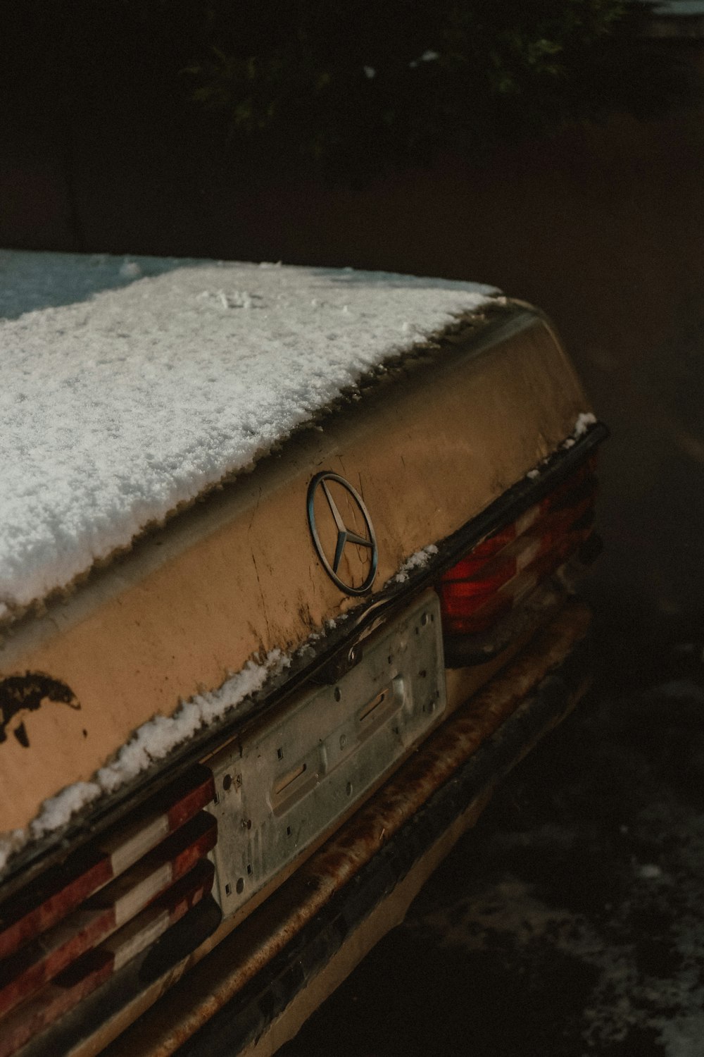 a car covered in snow with a mercedes emblem