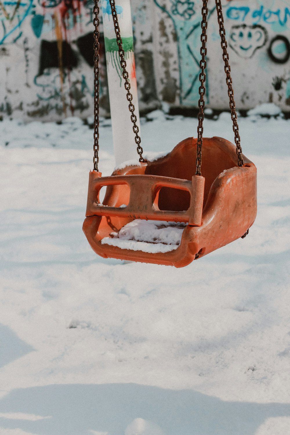 a rusted swing hanging from a chain in the snow