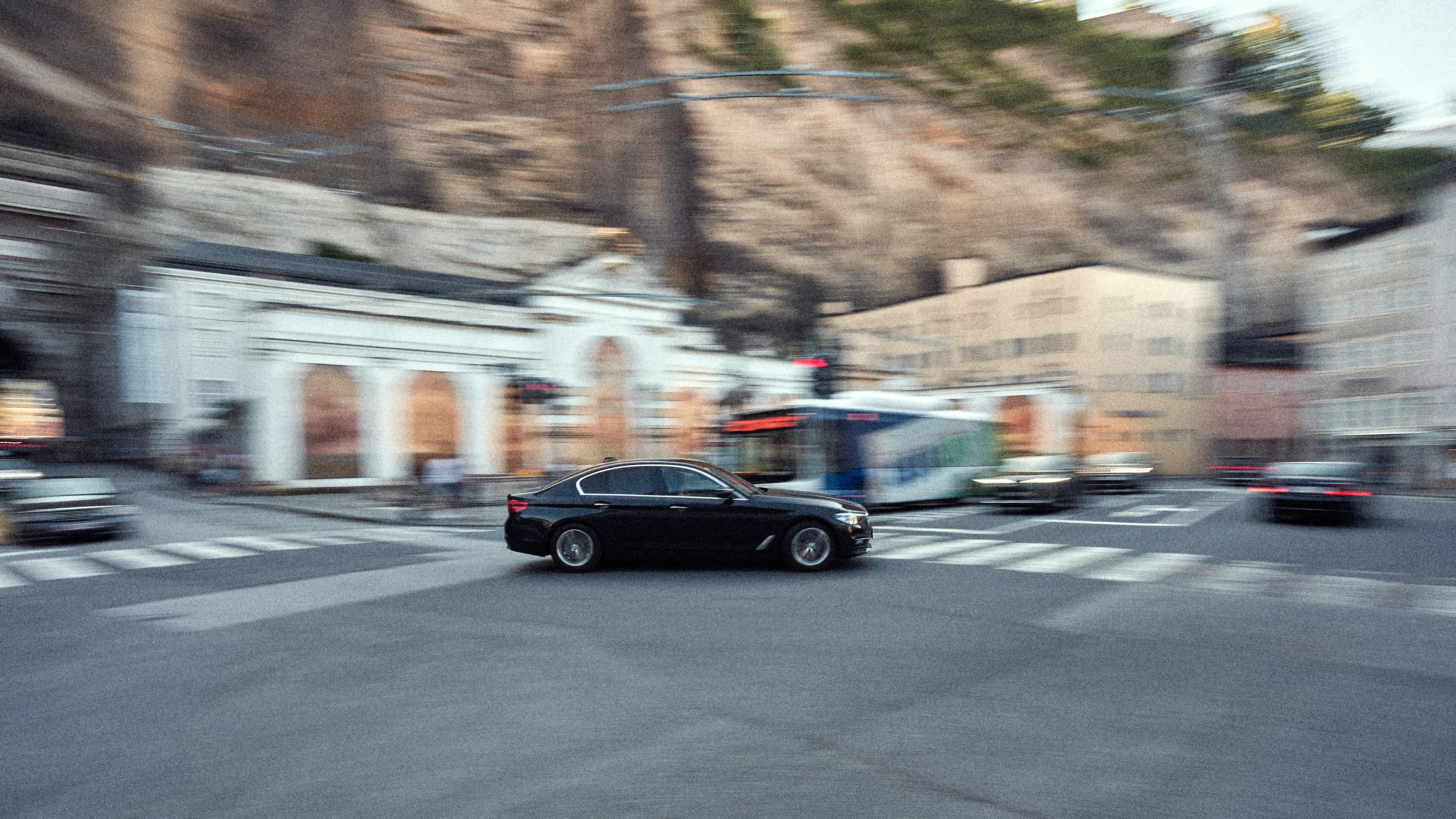 a black car driving down a street next to tall buildings
