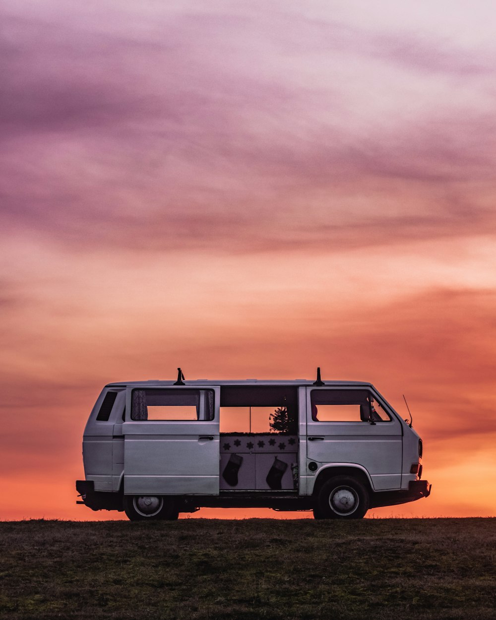 a van parked in a field with a sunset in the background
