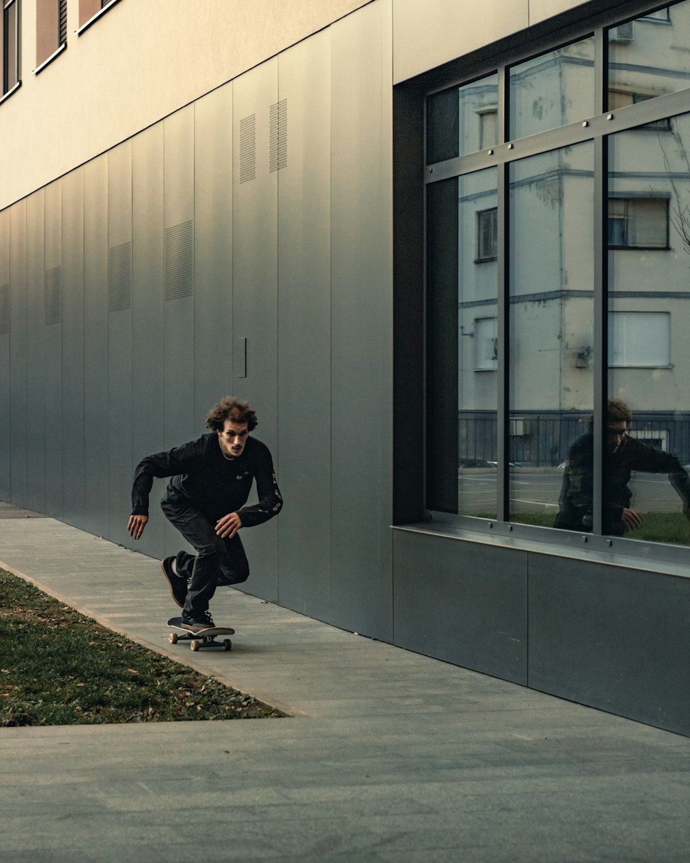 a man riding a skateboard down a sidewalk next to a building