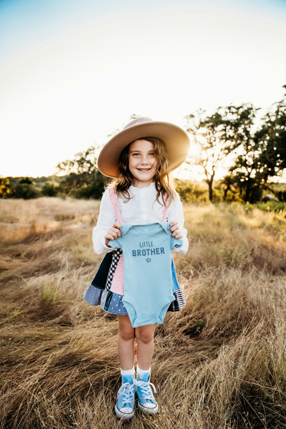a little girl wearing a hat and holding a blue shirt