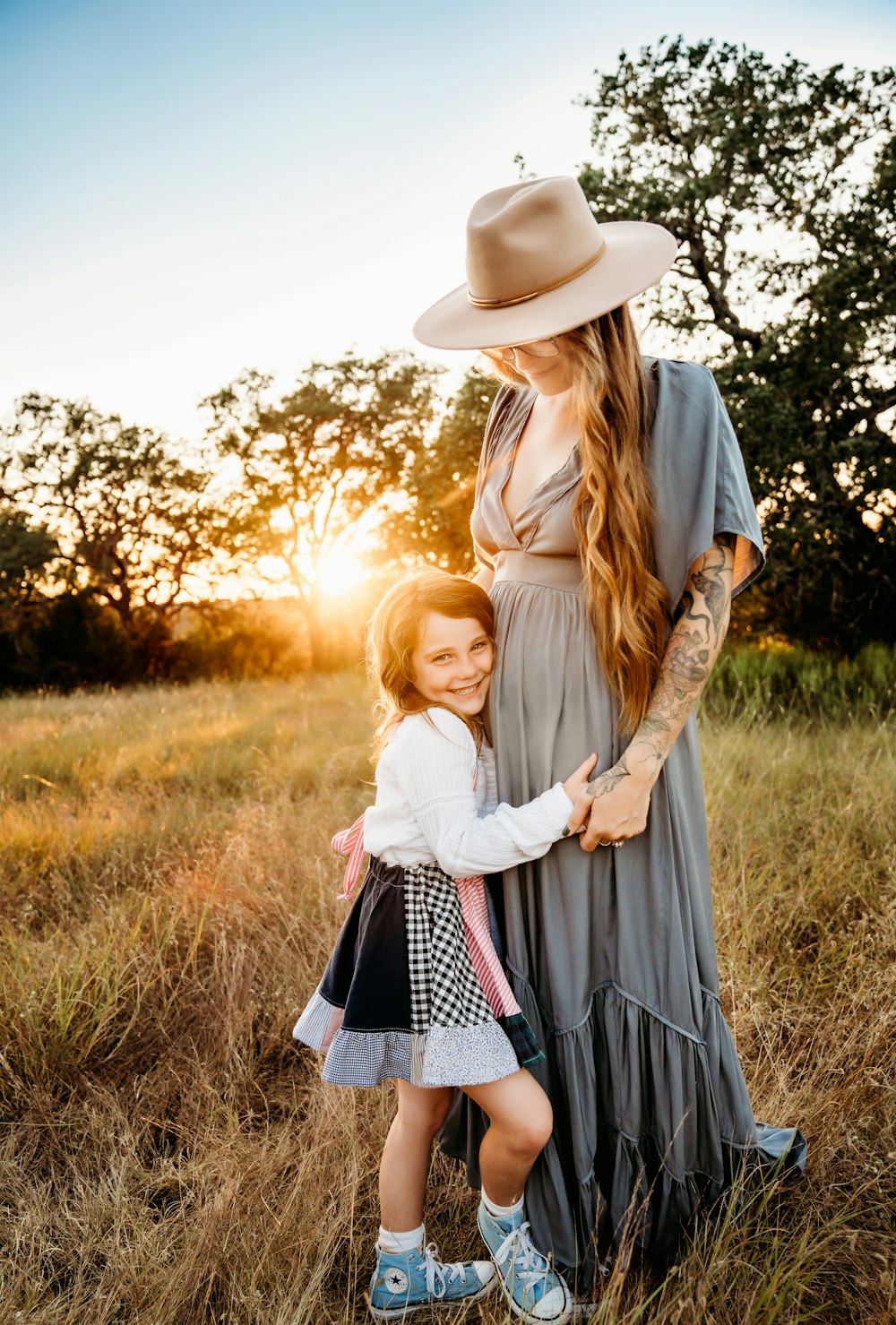 a woman and a little girl standing in a field