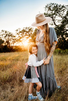 a woman and a little girl standing in a field