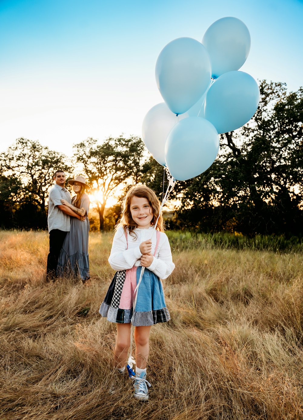 a little girl holding a bunch of white balloons