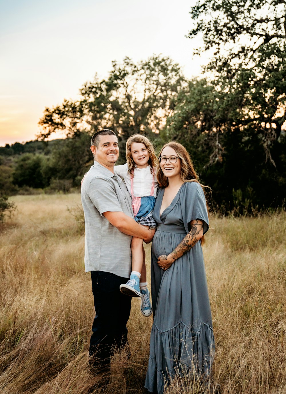 a family poses for a photo in a field at sunset