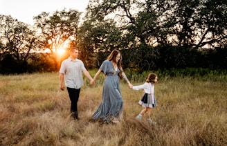 a family walking through a field holding hands