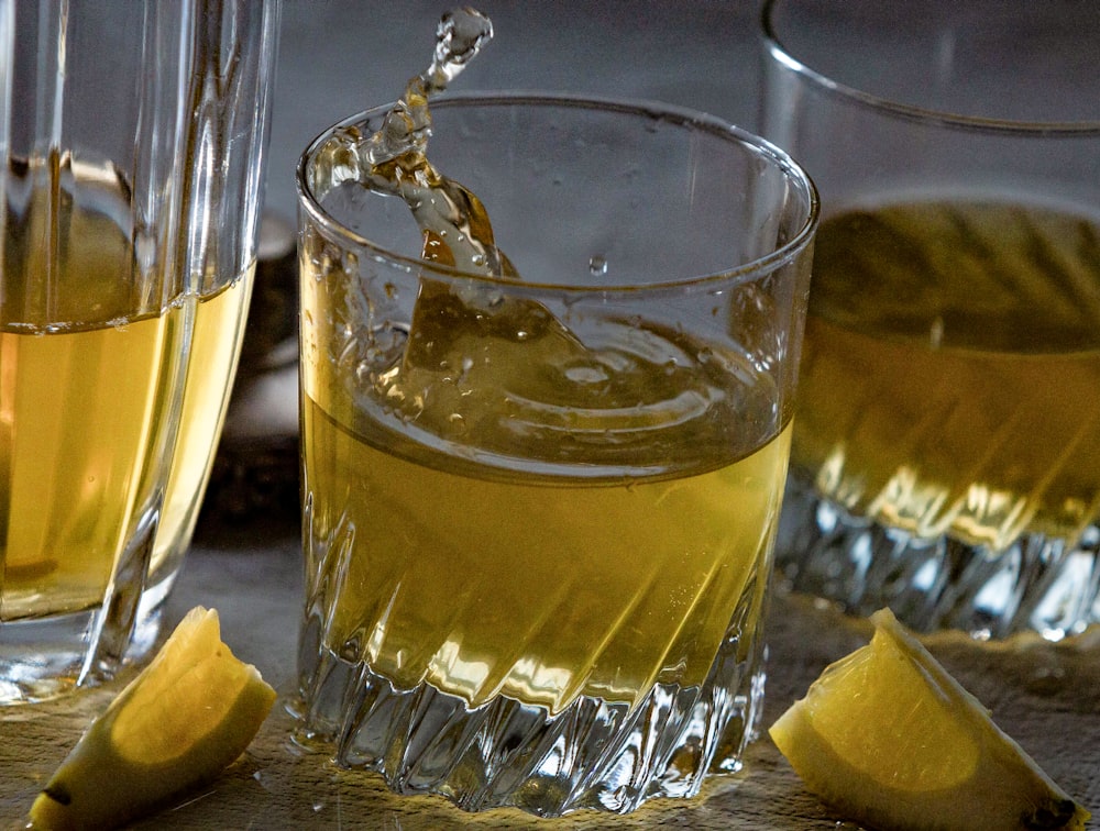 a glass filled with liquid next to sliced lemons