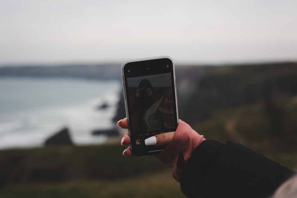 a person holding up a cell phone to take a picture