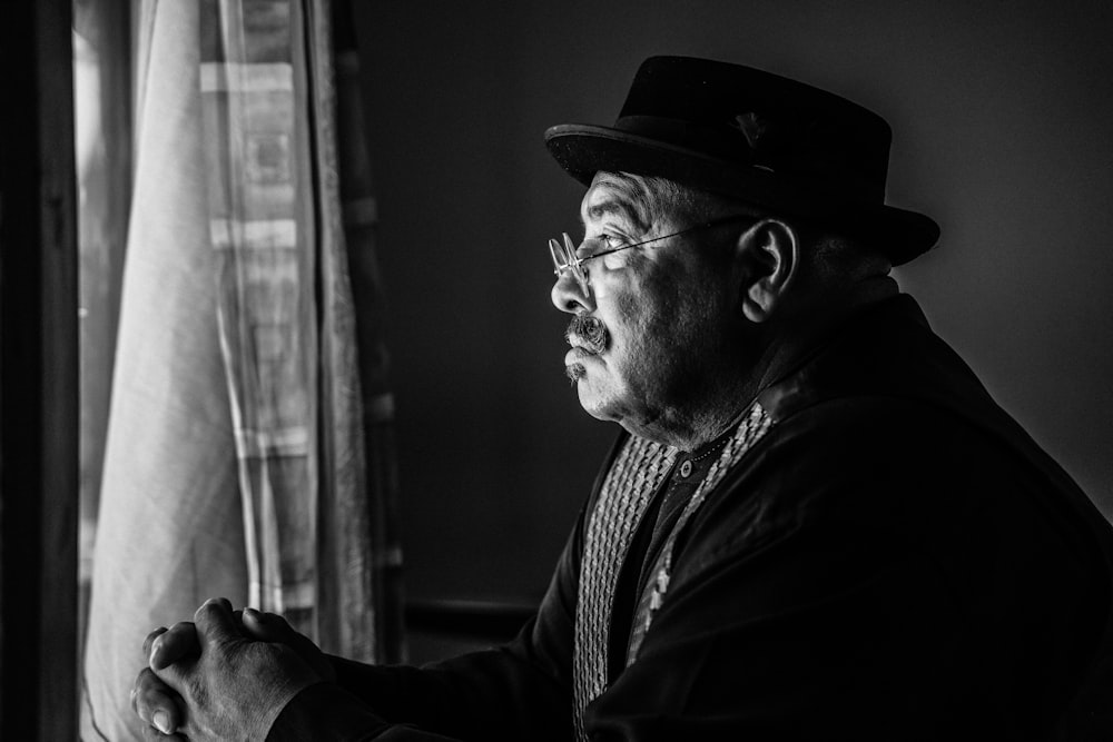 a man in a top hat looking out a window