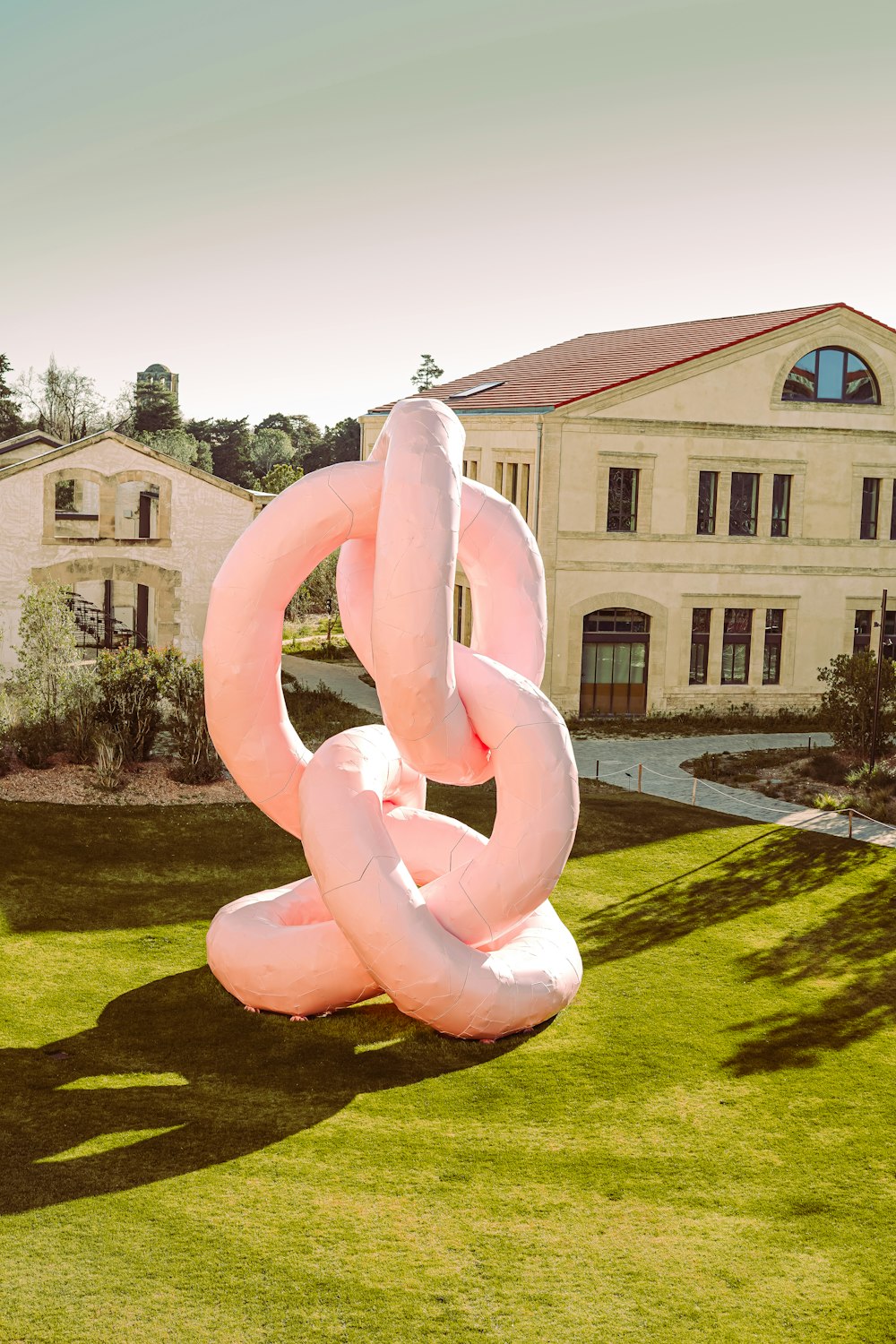 Une grande sculpture rose au milieu d’une pelouse