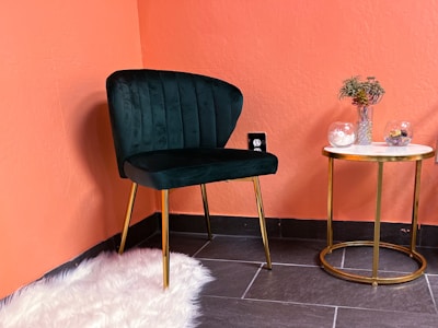 A cozy living room corner with a velvet emerald green armchair and gold-accented side table.
