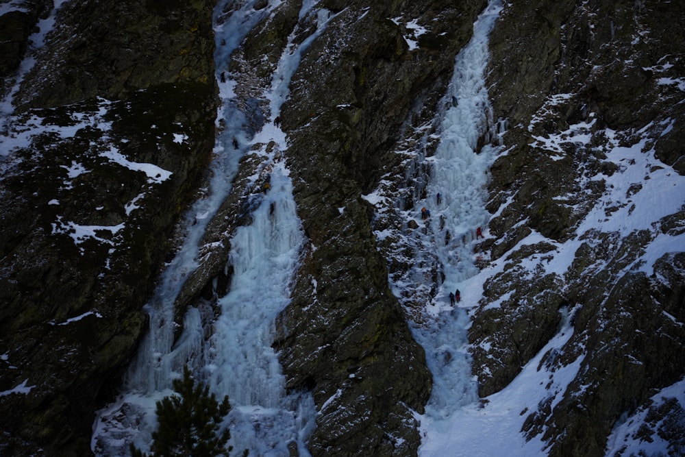 a man climbing up the side of a snow covered mountain