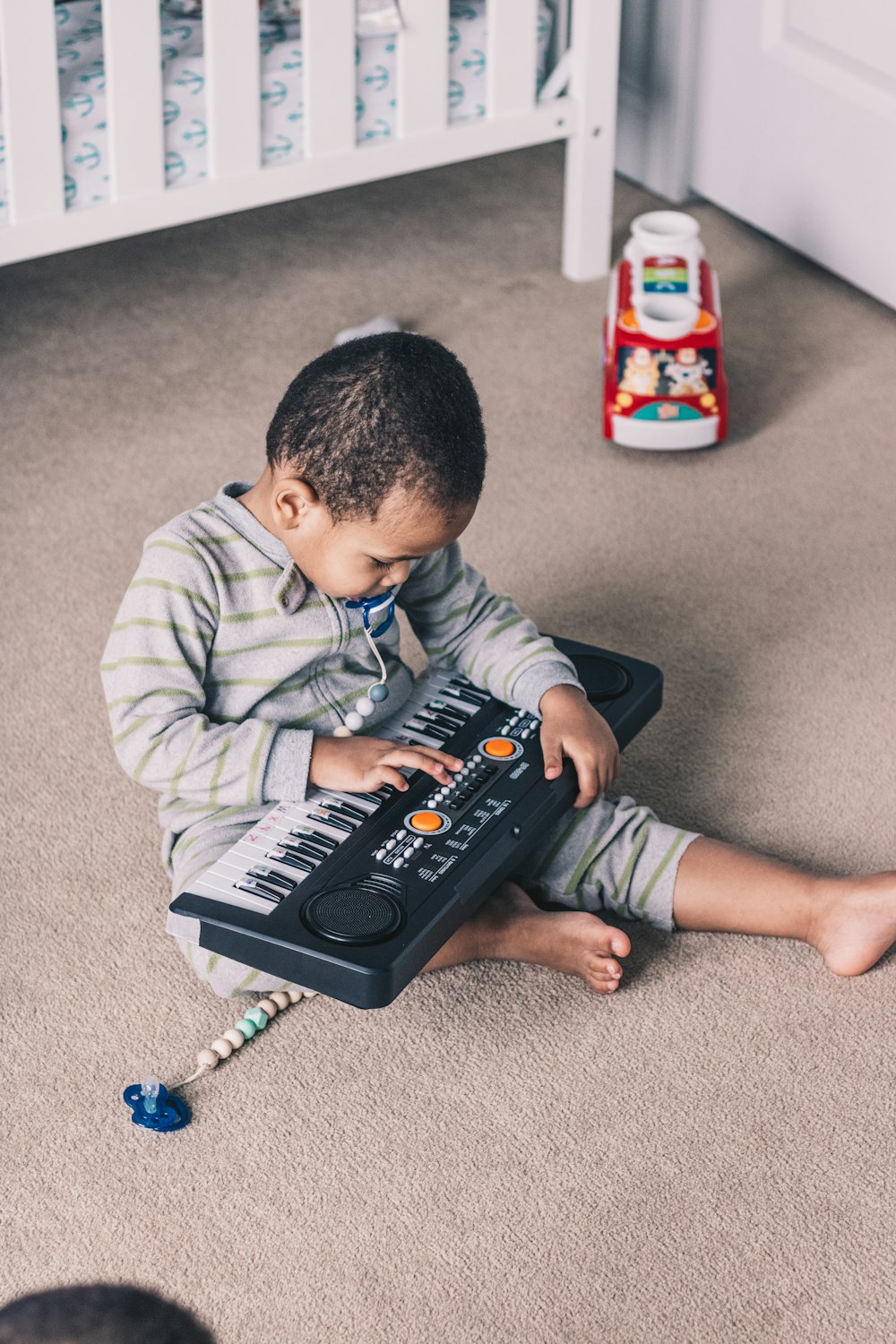 a little boy sitting on the floor playing with a keyboard