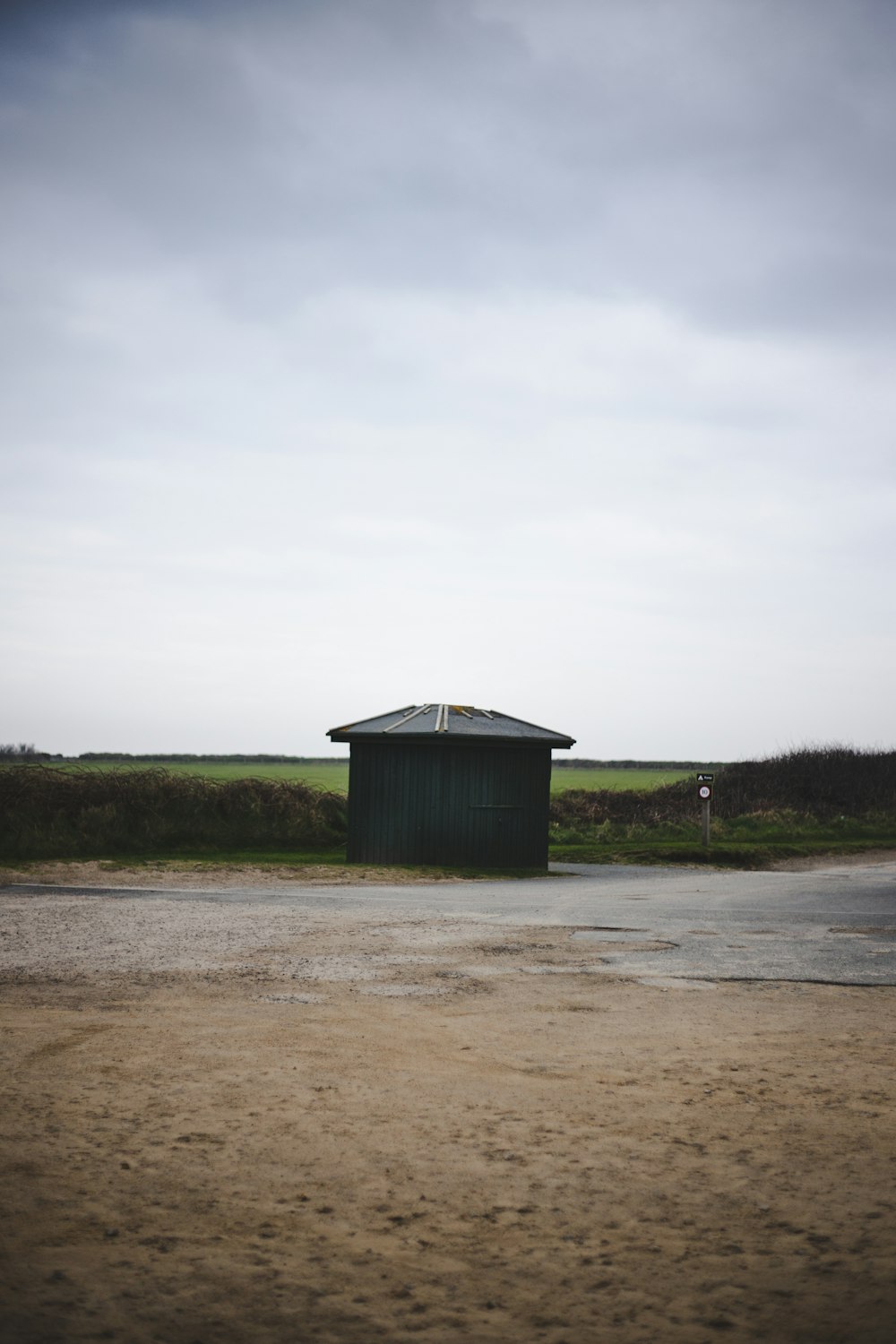 a small green building sitting in the middle of a field