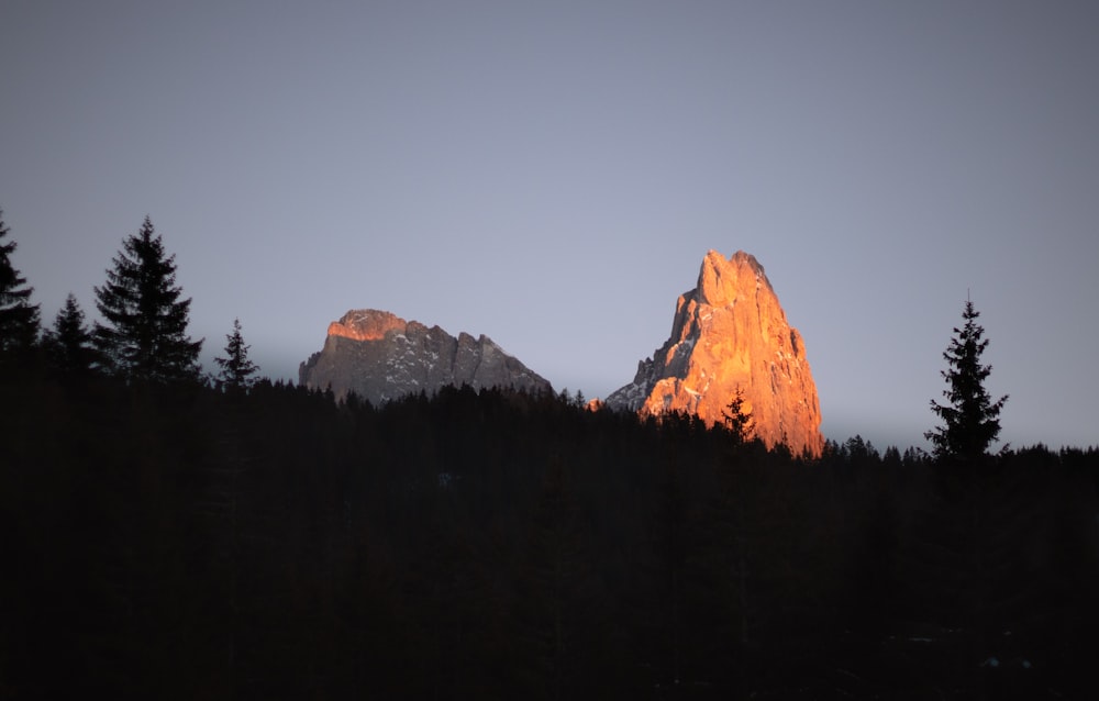 a mountain with trees in the foreground and a sky in the background