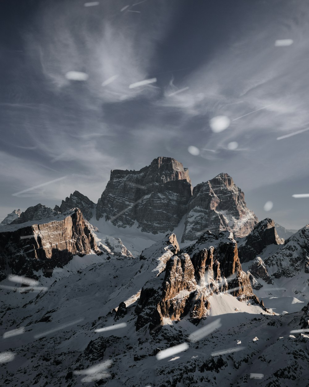 a snow covered mountain range under a cloudy sky