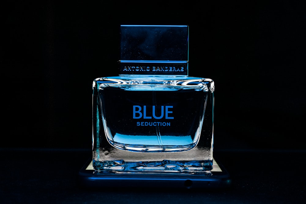 a blue bottle of perfume sitting on top of a table