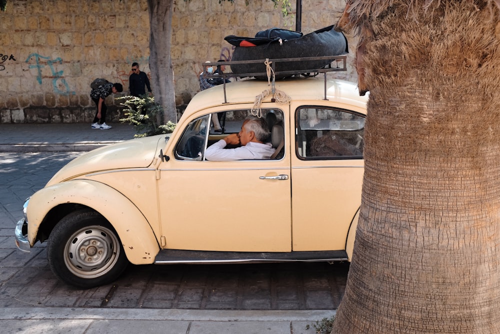 an old yellow car with luggage on top of it