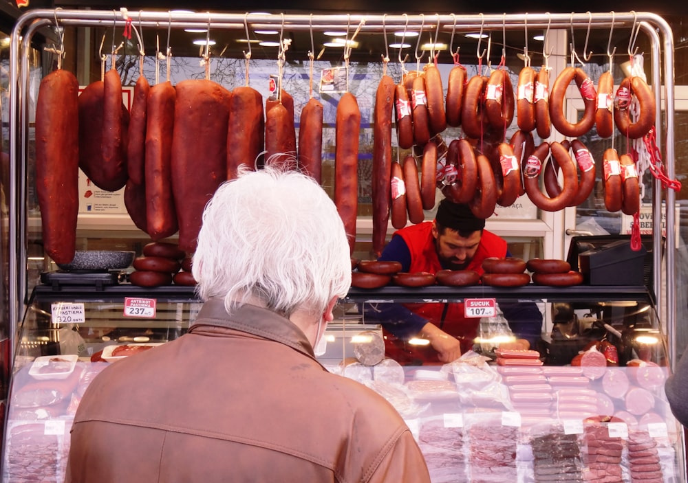 a man standing in front of a display of sausages