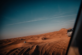 A thrilling desert landscape showcasing off-road vehicles racing across sandy dunes under a clear blue sky.