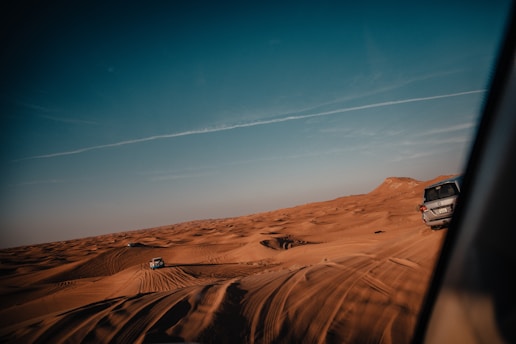 A thrilling desert landscape showcasing off-road vehicles racing across sandy dunes under a clear blue sky.