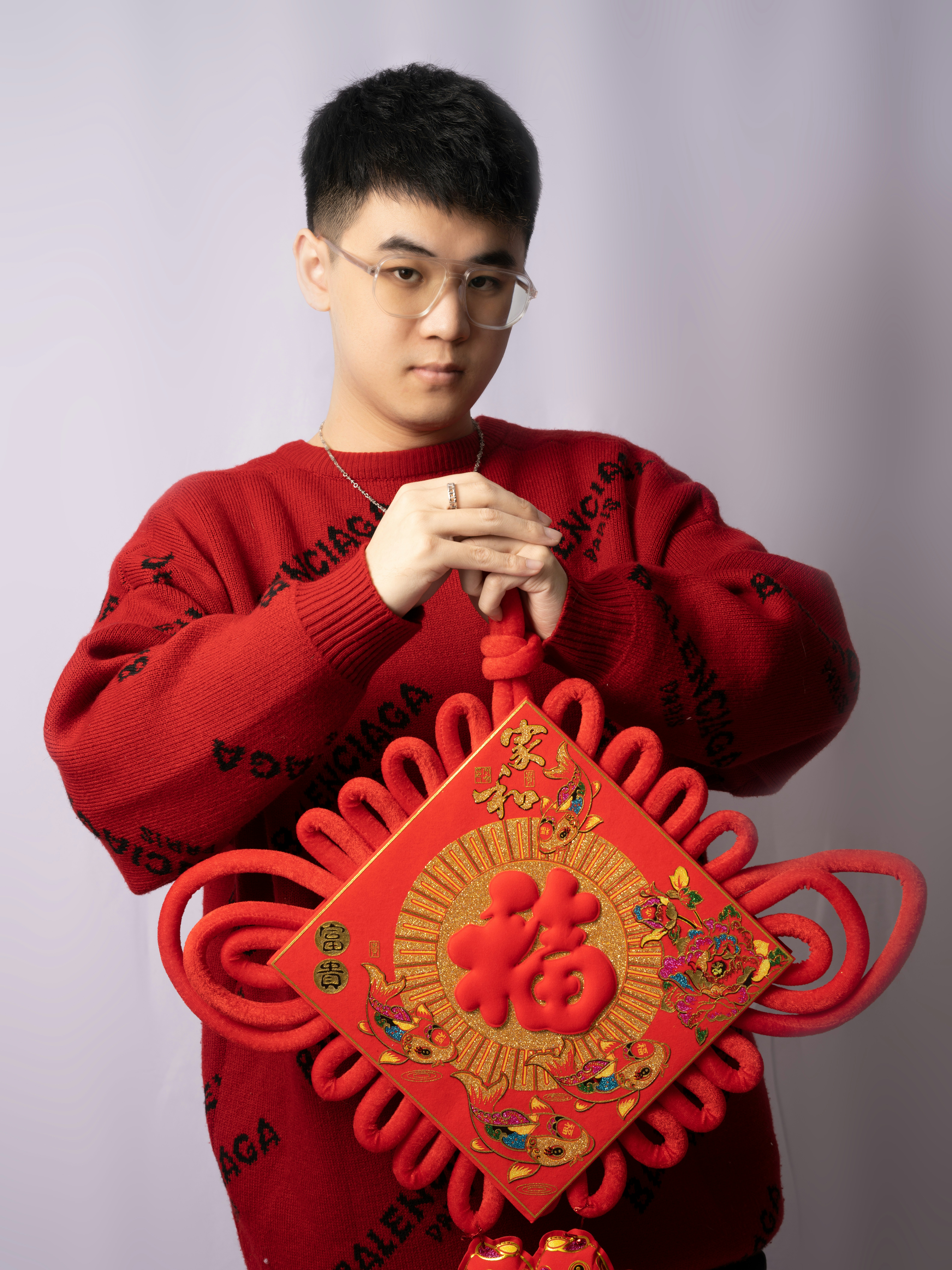 a man in a red sweater holding a red and gold decoration
