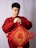 a man in a red sweater holding a red and gold decoration