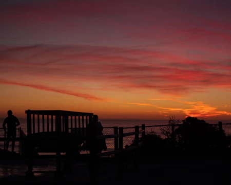A sunset view over the Bimbia heritage site, with silhouettes of visitors reflecting.