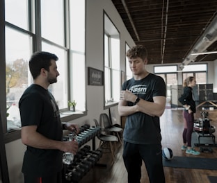a man standing next to another man in a gym